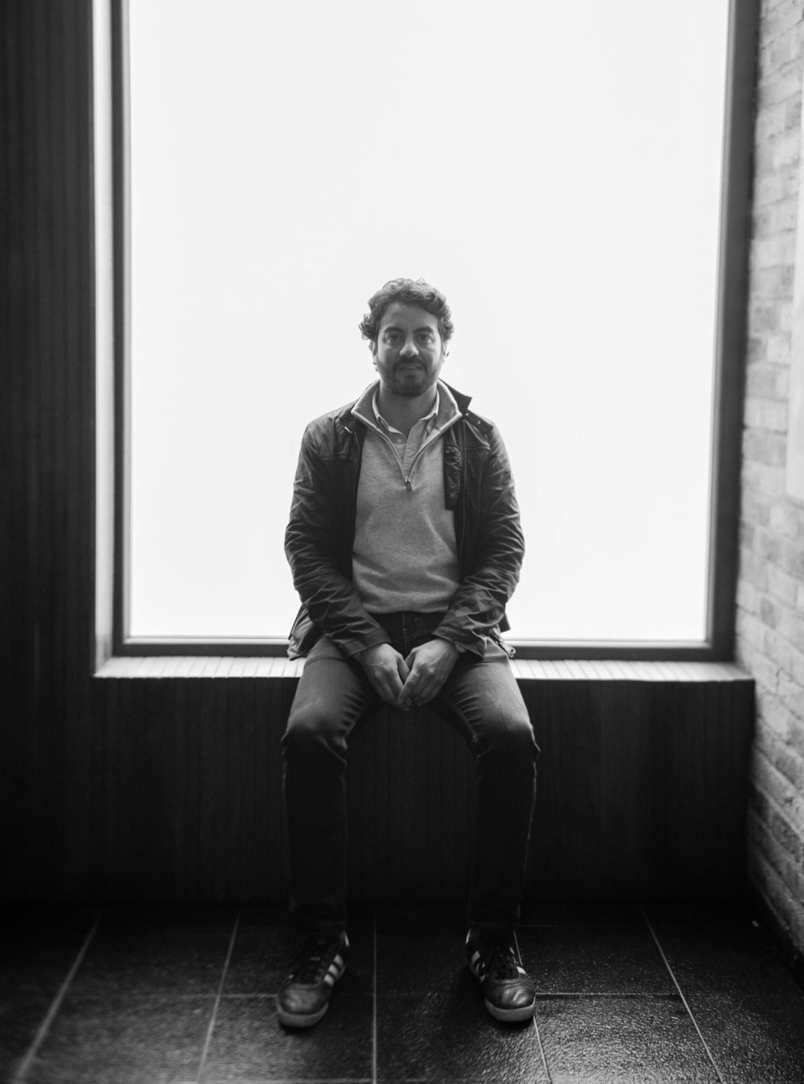 Black-and-white portrait of architect Santiago Muñoz seated by a window